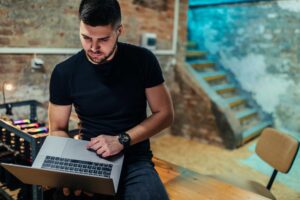 homem com notebook na mão centrado sobre uma mesa