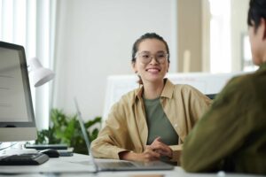 mulher sorrindo para outra pessoa em um ambiente de trabalho